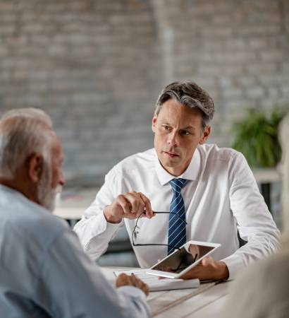 Do you agree with these loan terms? Insurance agent communicating with senior clients while showing the something on a touchpad during a meeting in the office.