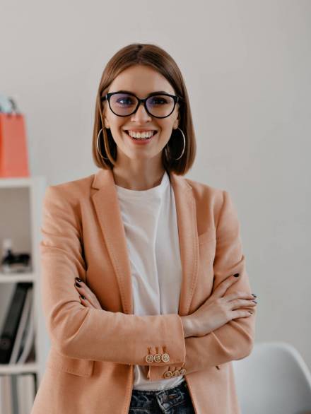 Close-up portrait of smiling short-haired business woman in white t-shirt posing with arms crossed in white office