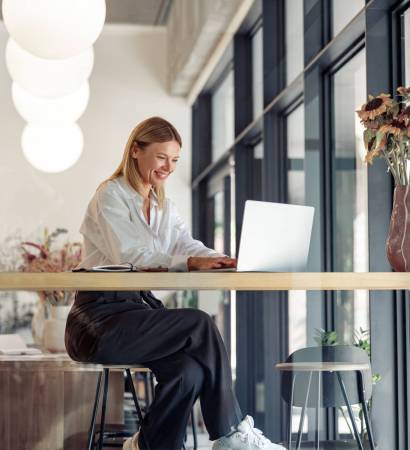 Smiling woman entrepreneur working on laptop in cozy coworking space interior
